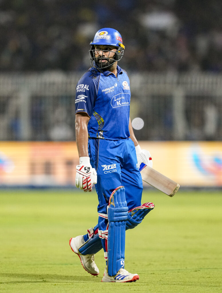 Indian cricket player in blue uniform with helmet and bat on the field during a match.