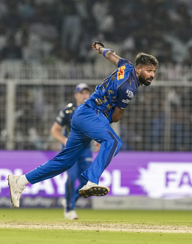 Indian cricketer in blue uniform diving to catch the ball during a match.