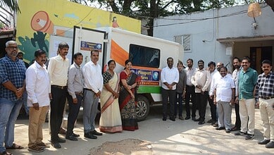 A woman and a group of men standing beside a decorated vehicle with a "Passport Seva" sign in an outdoor.