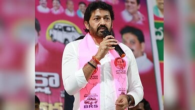 KCR speaking into a microphone during a political rally, wearing a pink scarf with images of leaders, in.