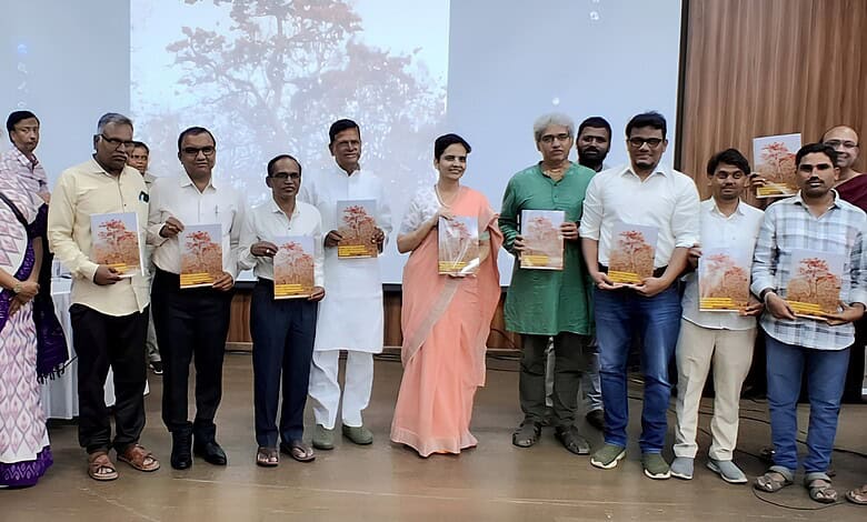 A woman in a peach saree and men in formal attire holding copies of The Siasat Daily at a book launch eve.