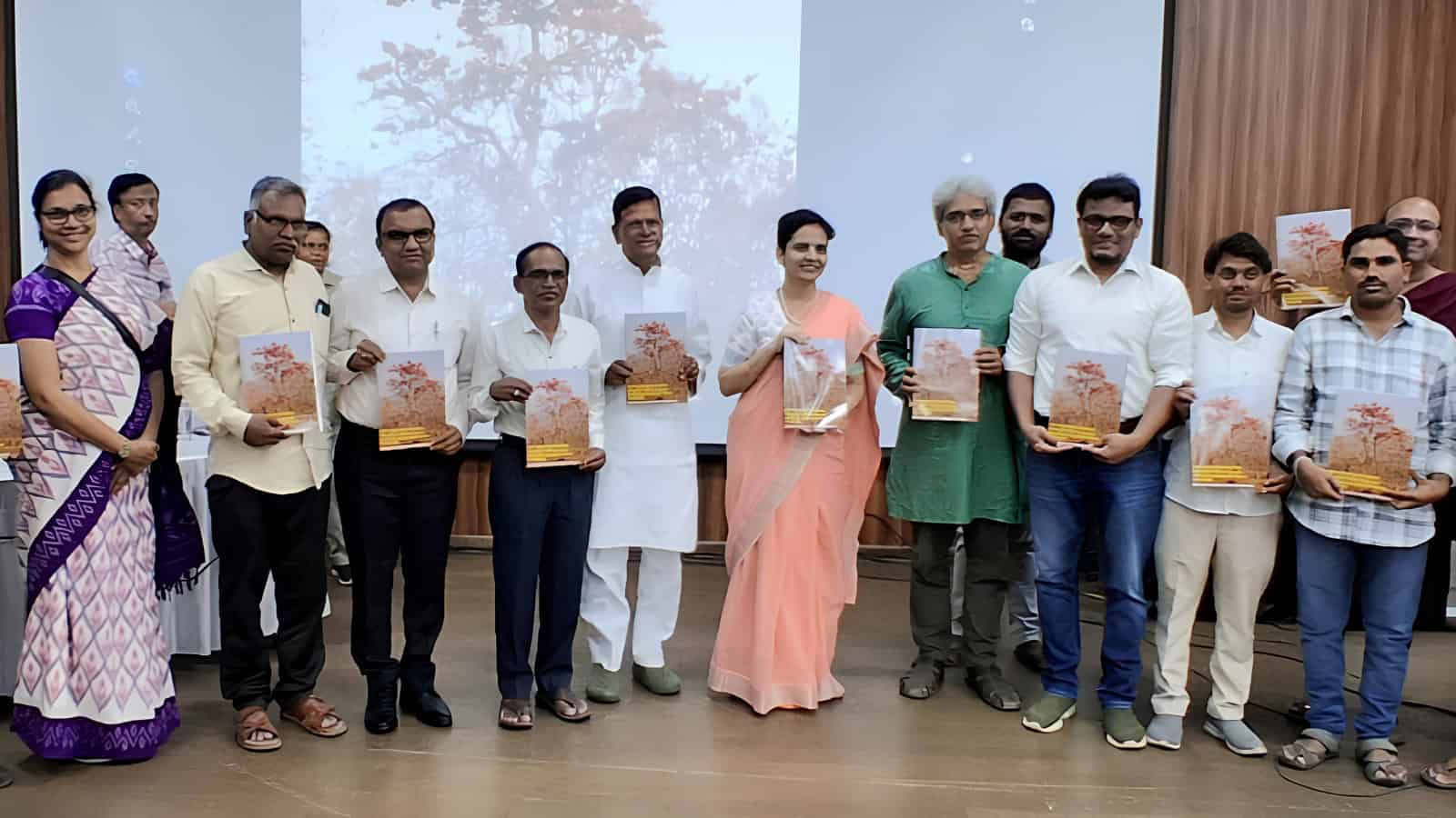 A woman in a peach saree and men in formal attire holding copies of The Siasat Daily at a book launch eve.