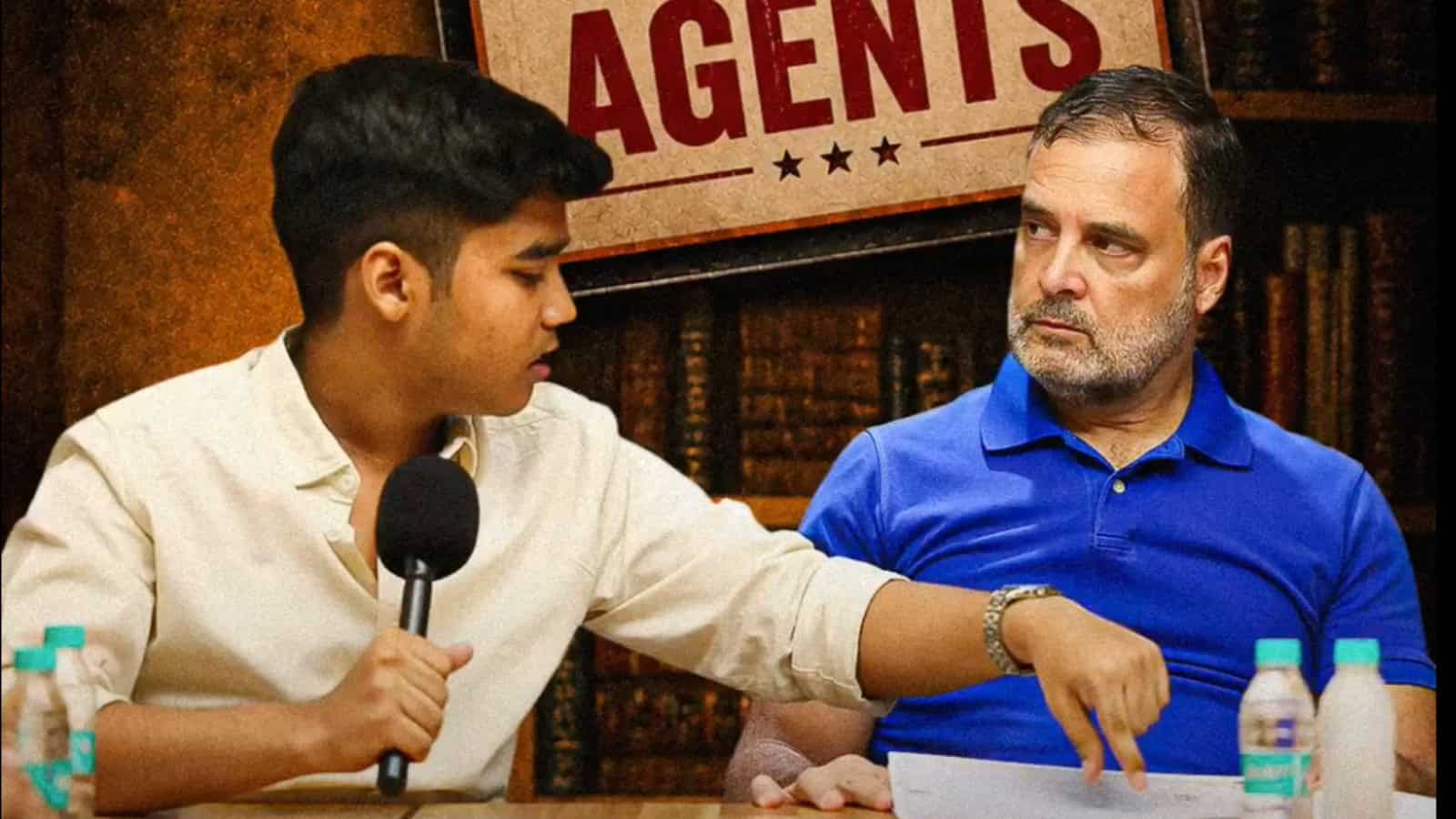 A young man interviewing an older man at a press conference or media event, with a sign reading