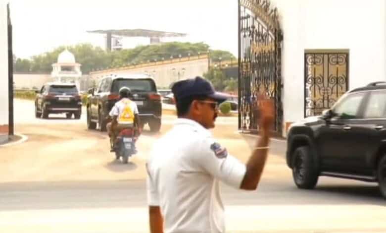 Security officer managing vehicle movement at entrance gate with parked cars and a motorcycle.