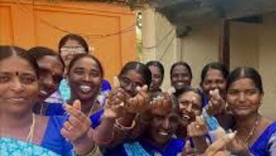 Community health workers in blue uniforms administering vaccines to smiling villagers outdoors.