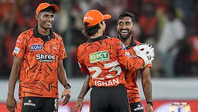 Excited cricket players celebrating victory during a match in vibrant orange uniforms.