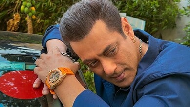 A man in a blue shirt resting his head on his arm outdoors.