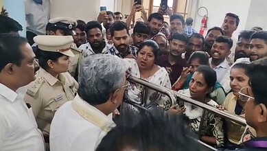 A man speaking to a crowd of people, including police officers, in an indoor setting.