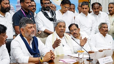 Prominent Indian politician speaking at a press conference with colleagues and media in the background.