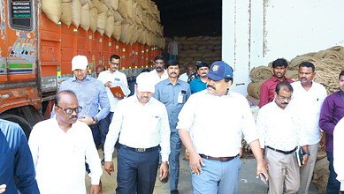 Civil Supplies Commissioner inspecting paddy at procurement centre with officials and workers present.