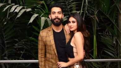 A stylish man and woman posing together at The Siasat Daily event, surrounded by lush green plants.