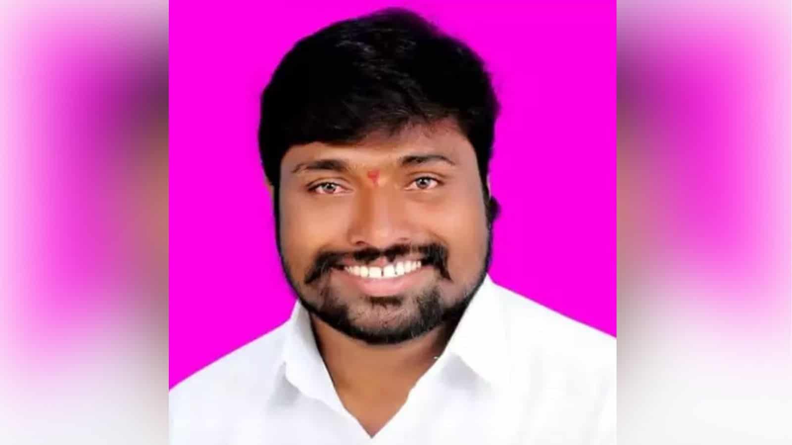 Bright smiling man with dark hair and beard wearing a white shirt against a vibrant pink background.