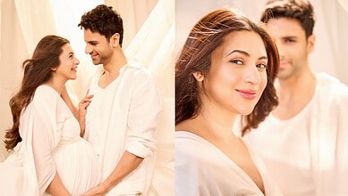 A pregnant woman and her partner smiling and looking at each other in a bright, cozy room.