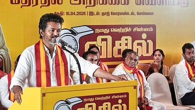TVK leader speaking at Tamil Nadu election rally with supporters, promoting promises of gold and free cyl.