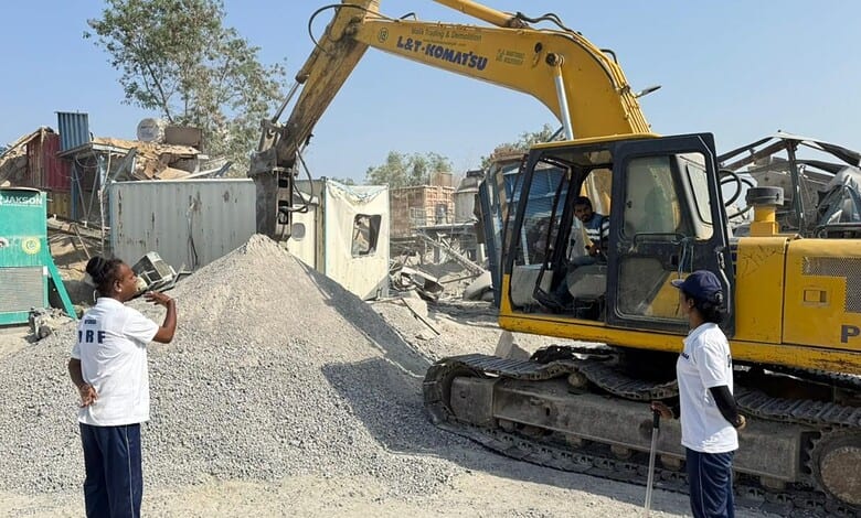 Excavator demolishing a structure at a construction site in an urban area.