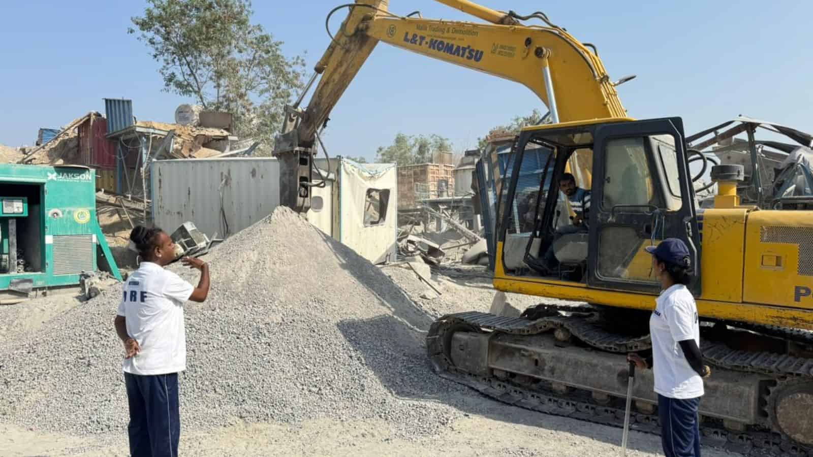 Excavator demolishing a structure at a construction site in an urban area.