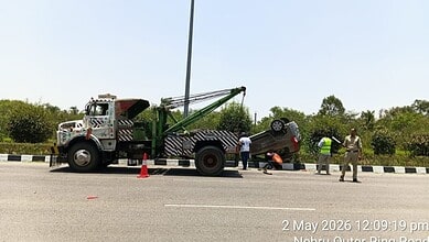 Tow truck lifting a damaged car after a crash on Hyderabad road, with officials managing the scene.