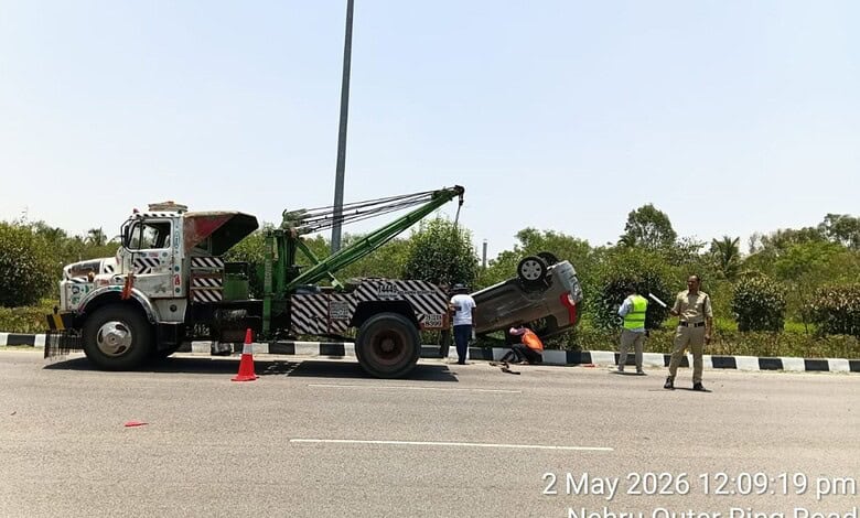 Tow truck lifting a damaged car after a crash on Hyderabad road, with officials managing the scene.