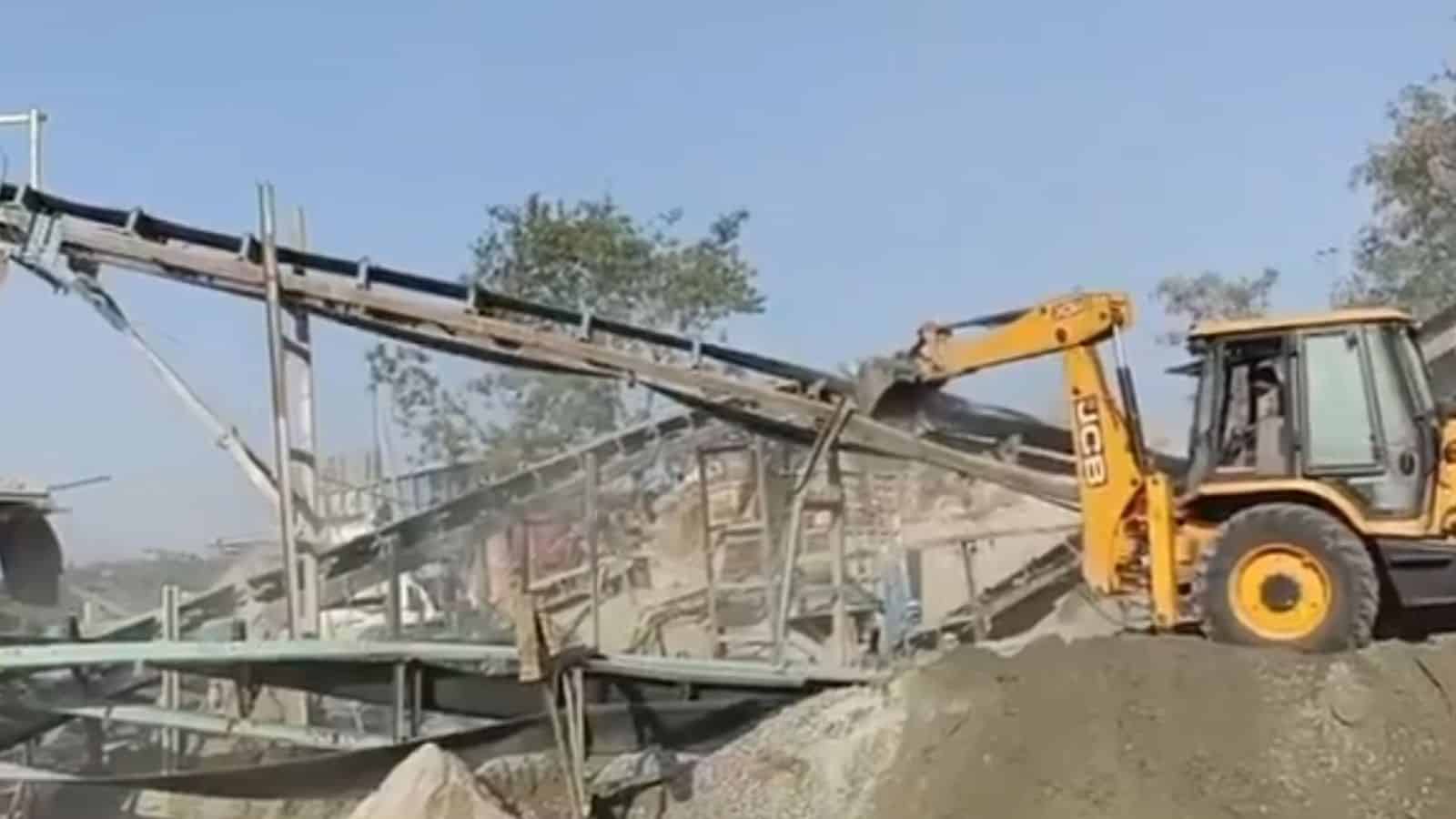 Excavator demolishing illegal mining structures in Hyderabad as part of anti-mining operations.