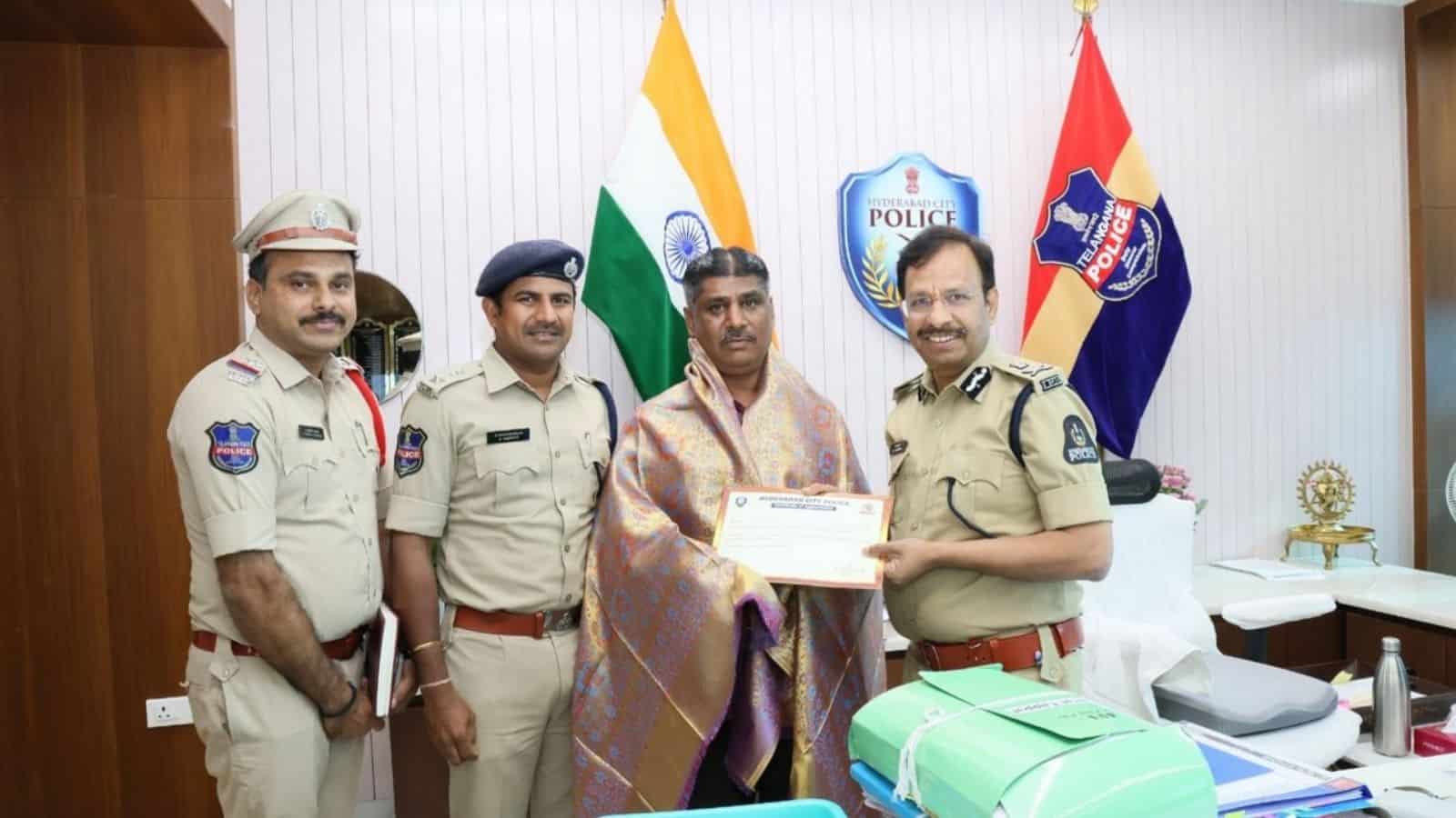 Police officers with official uniforms and a man receiving an award in an office setting.