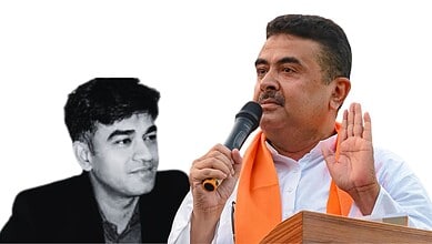A man speaking into a microphone with a serious expression, wearing a white shirt and orange scarf.