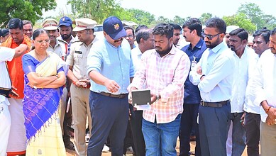 Government officials and farmers discussing paddy procurement and financial aid distribution outdoors.