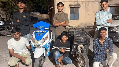 Young men standing with bikes and scooters on a street in Hyderabad, involved in illegal bike stunts.
