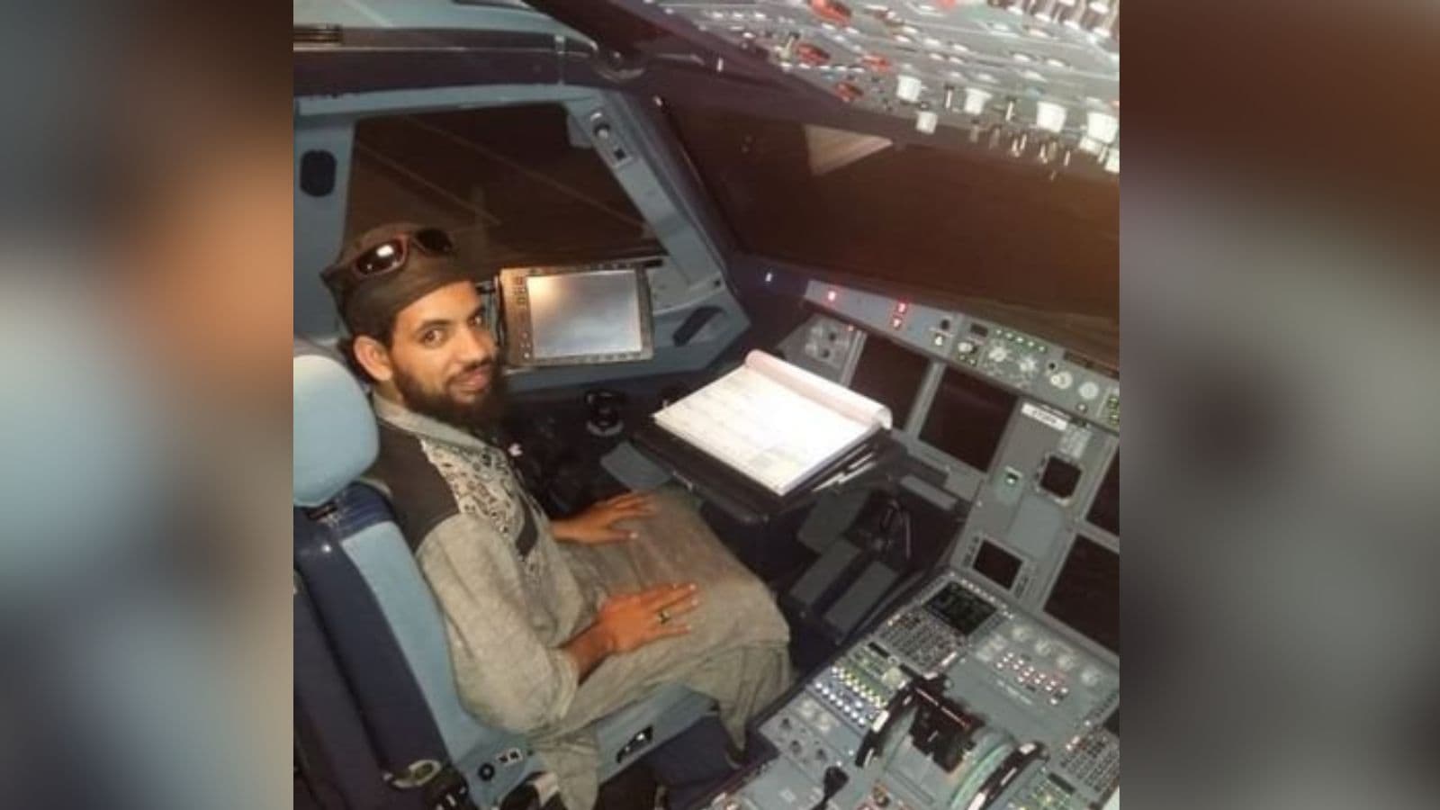 A man sitting in an aircraft cockpit, operating controls and instruments, with a focused expression.