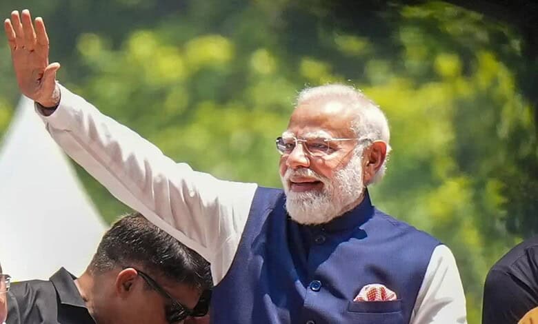 India's Prime Minister Narendra Modi waving to supporters outdoors during a public event.