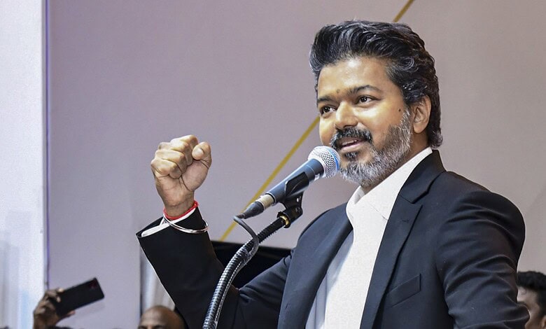 A young man in a black suit speaking passionately at a podium during a political event.