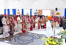 Six Sikh couples participating in a mass wedding ceremony in Hyderabad, with family and friends present.