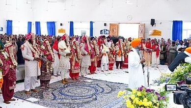 Six Sikh couples participating in a mass wedding ceremony in Hyderabad, with family and friends present.