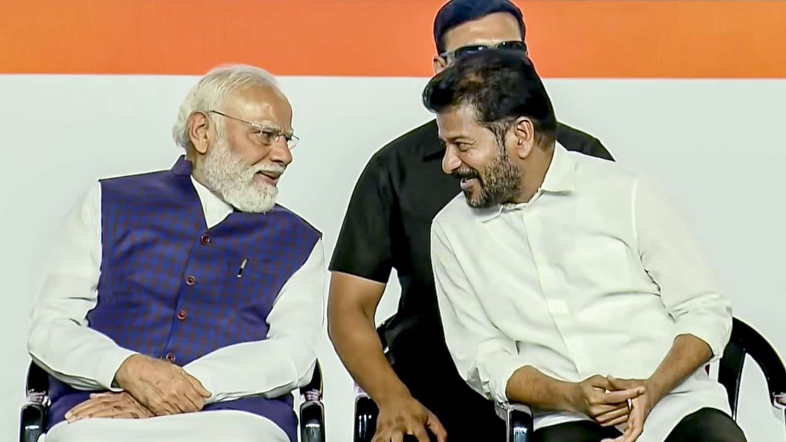 Indian Prime Minister Narendra Modi smiling and engaging with Telangana Chief Minister Revanth Reddy duri.