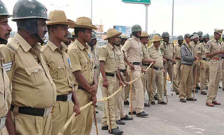 Police officers standing in a line during a formal event in Karnataka, wearing uniforms and hats, with so.