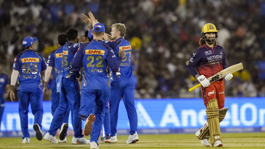 RCB cricket team celebrating a last-ball victory in IPL match against MI, with a Mumbai batsman walking o.