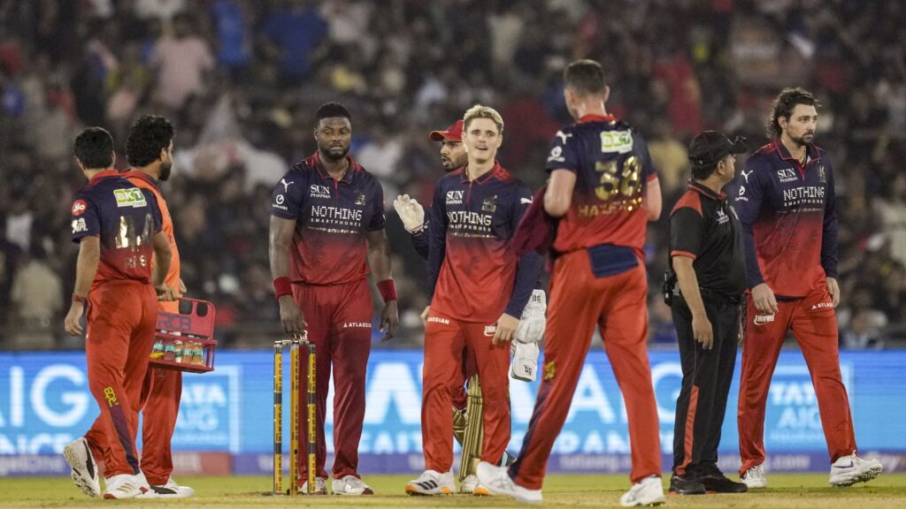 RCB cricket players celebrating last-ball IPL victory against MI on the field.