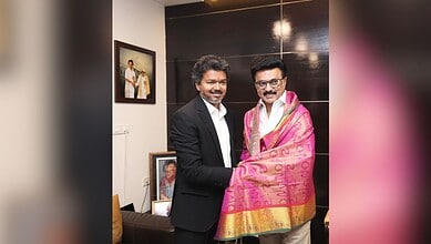 Celebration of cultural event with two men exchanging a traditional pink and gold shawl, smiling in an in.