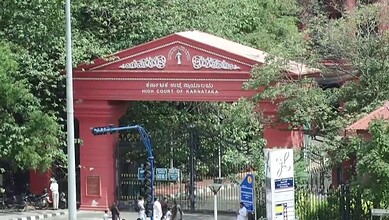 High Court of Karnataka entrance gate in Bangalore, surrounded by greenery and official signage.