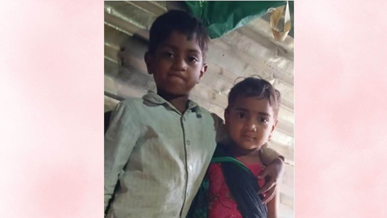 A young boy and girl standing together indoors, smiling at the camera, in a casual setting.