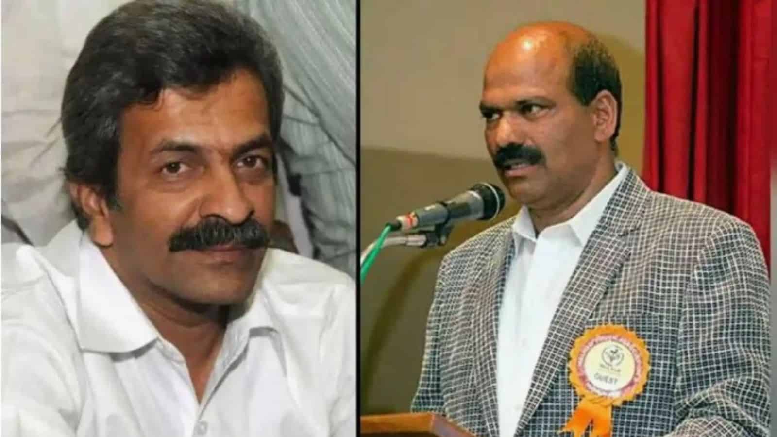 A man with a moustache and white shirt, and another man in a checked blazer speaking at a microphone duri.