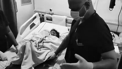 A young boy lying in hospital bed after dog attack in Hyderabad, with medical staff attending to him.
