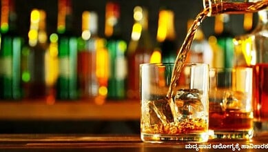 A refreshing glass of whiskey with ice cubes, with colourful bottles blurred in the background.