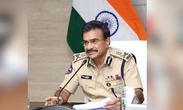 Indian police officer in uniform speaking at a press conference with the Indian flag in the background.