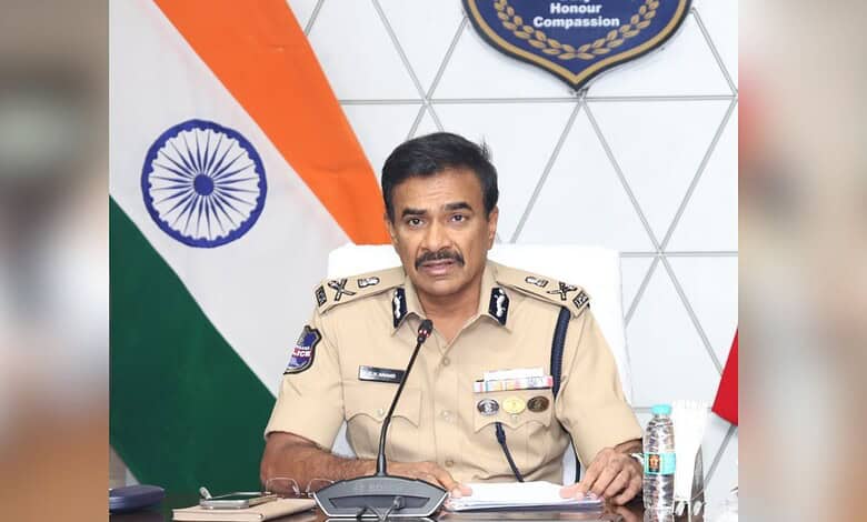 Indian police officer in uniform speaking at a desk with the Indian flag and a badge in the background.