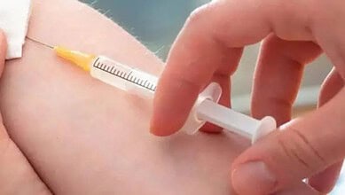 Vaccination injection being administered into a person's arm with a syringe.