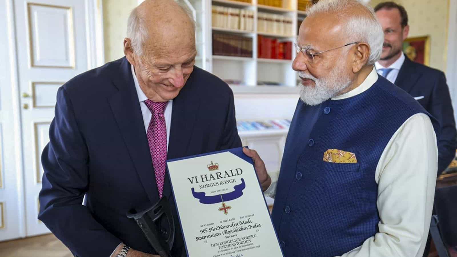 Honourable elderly man receiving award from Indian Prime Minister Narendra Modi at a formal event in Indi.