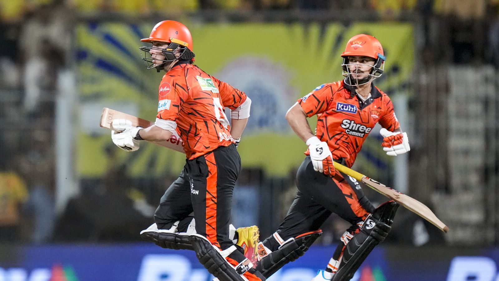 A cricket players in orange uniforms running on the field during a match.