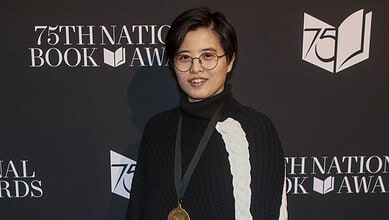 A woman with short black hair and glasses smiling at the 75th National Book Awards event.