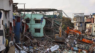 Urban building collapse with rescue operations and heavy machinery in a densely populated area.