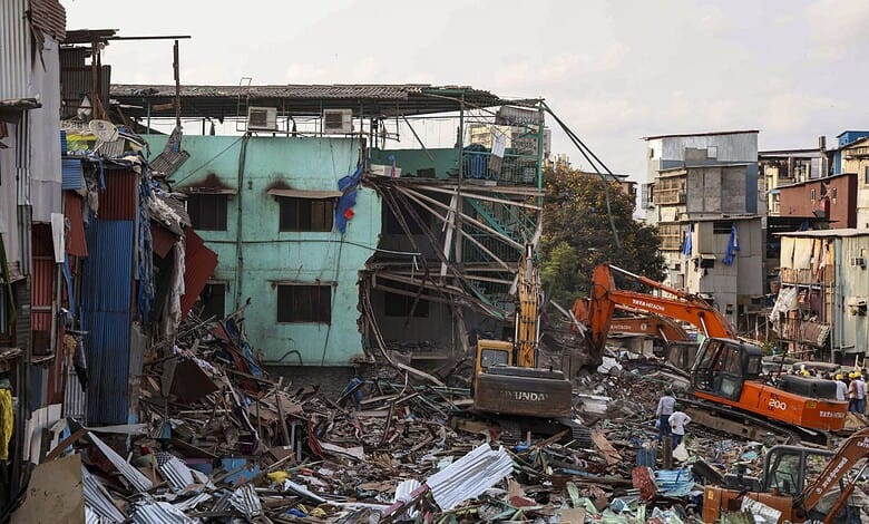 Urban building collapse with rescue operations and heavy machinery in a densely populated area.